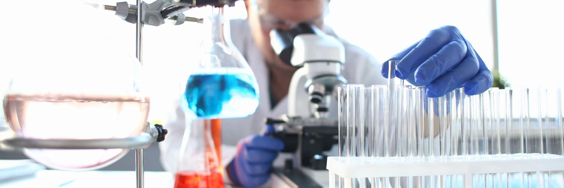 Portrait of a young chemist looking in binocular microscope looking for pathology analyzes patient at medical hospital for treatment disease tumors